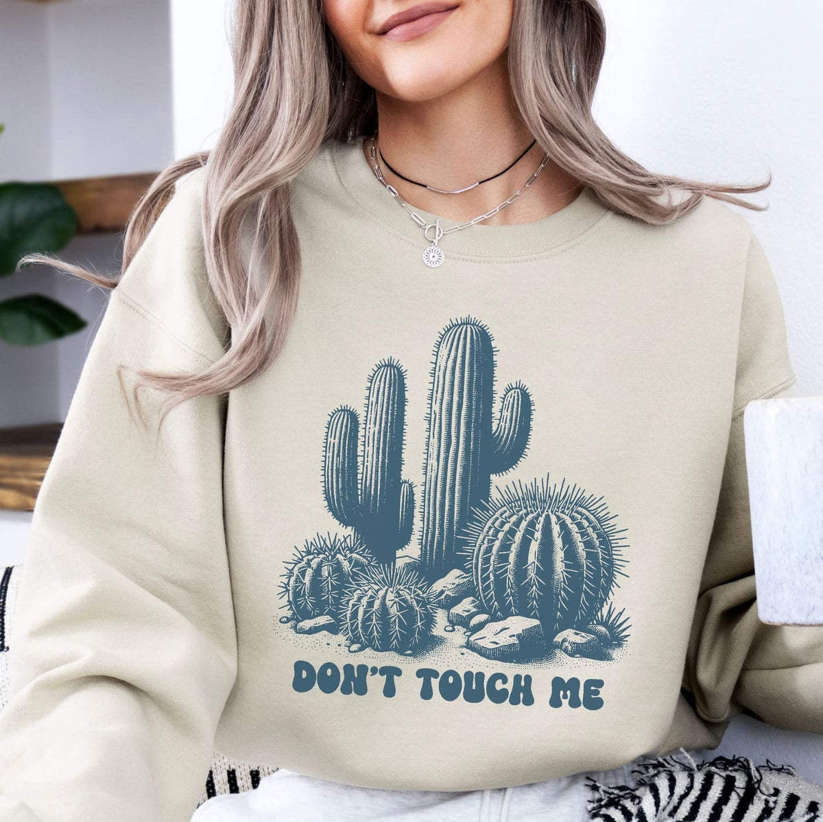 Person wearing a beige asexual sweatshirt with a cactus design and 'Don't Touch Me' text.