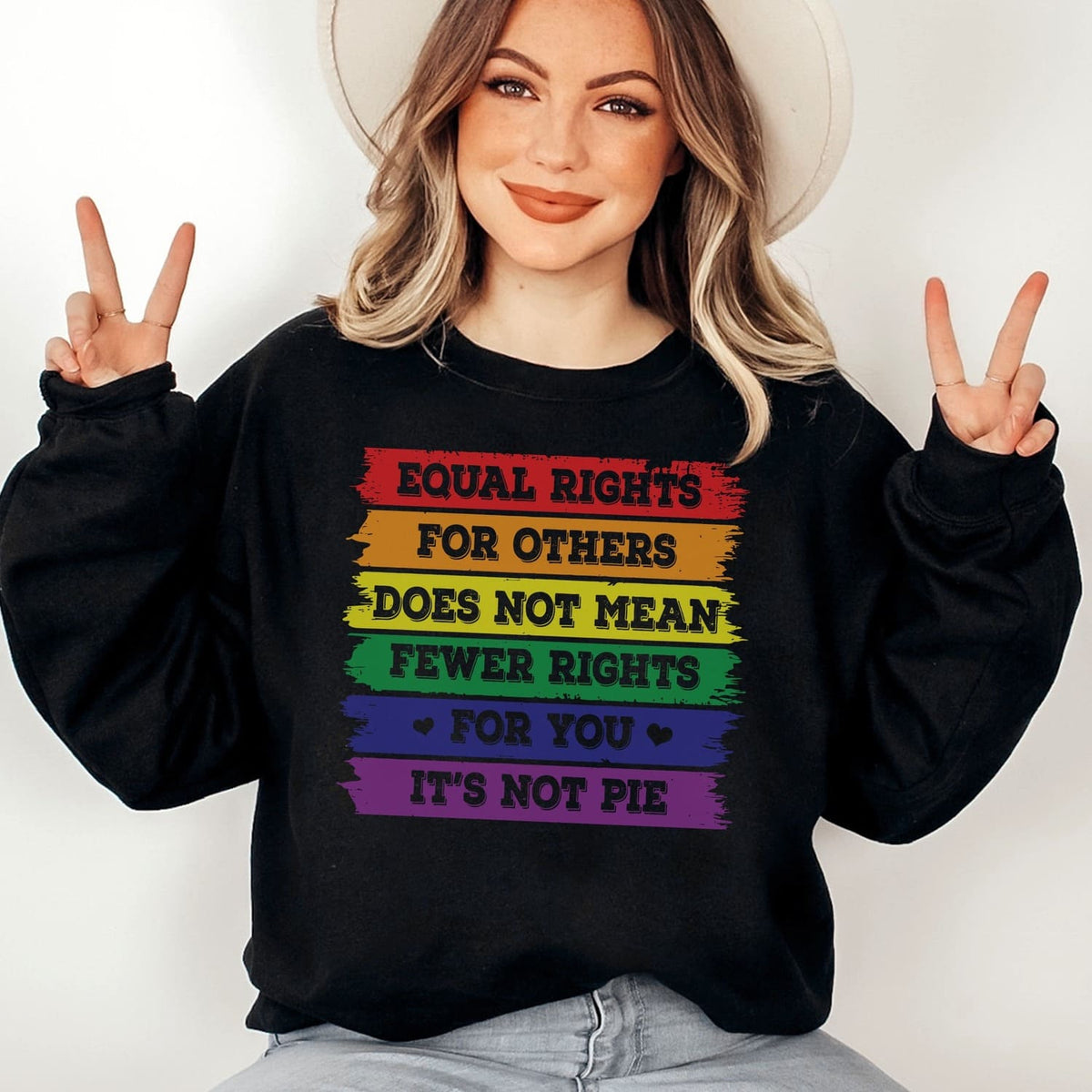 Person wearing a black LGBT pride  sweatshirt with rainbow-colored text on a white background
