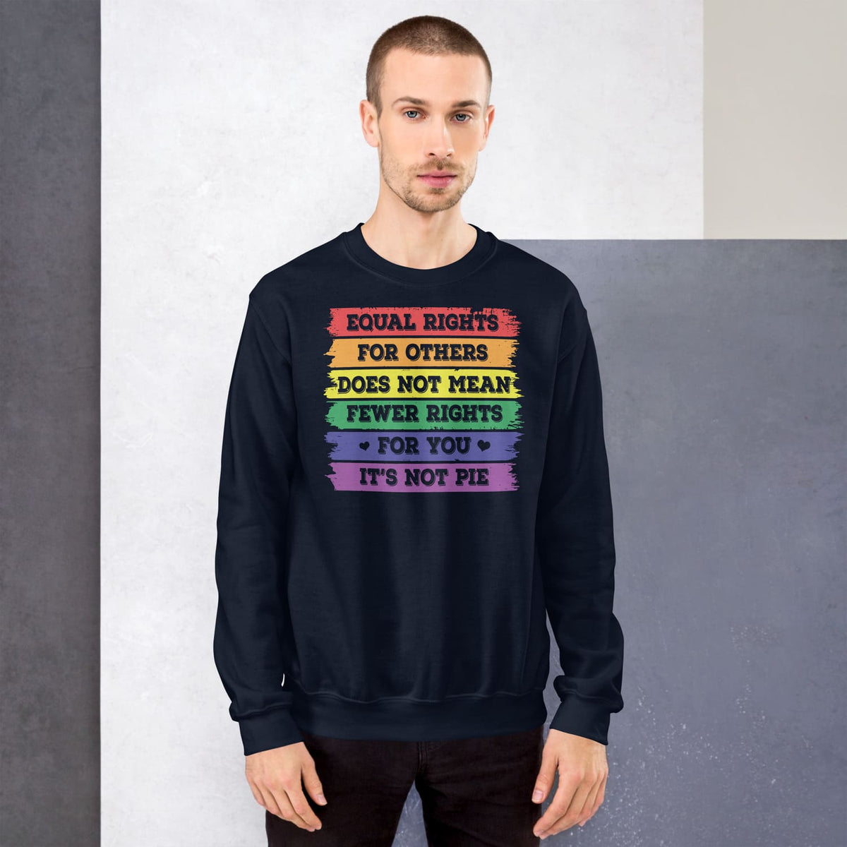 Person wearing a navy pride LGBTQ sweatshirt with rainbow-colored text on a gray background