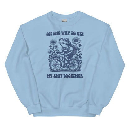 Light blue mental health sweatshirt with a graphic of a frog riding a bike and text on a white background