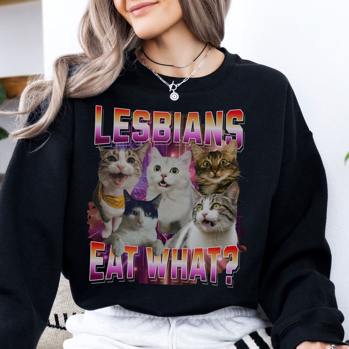Person wearing a black sweatshirt with a graphic of cats and text 'LESBIANS EAT WHAT?'