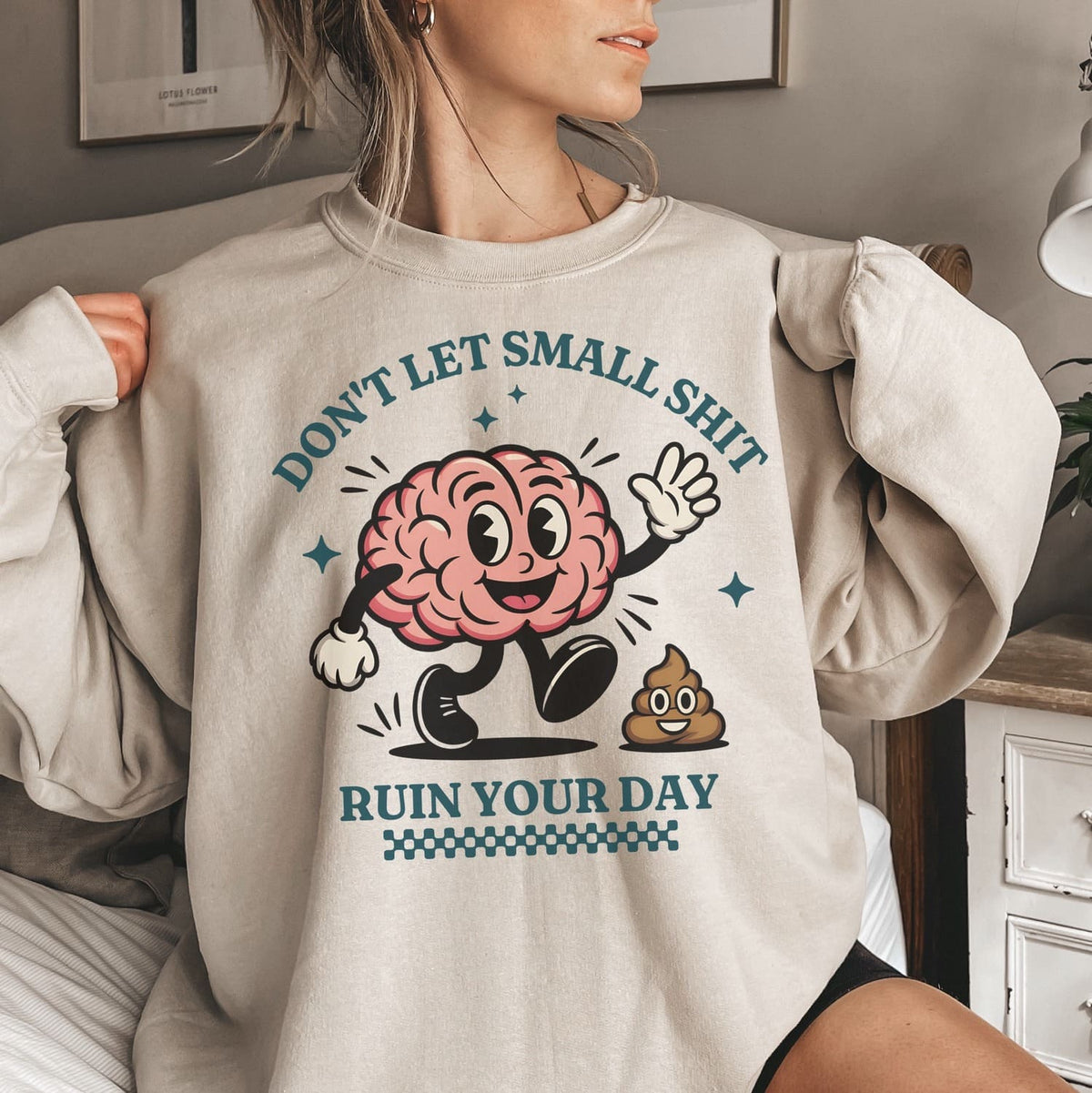 Person wearing a positivity sweatshirt with a cartoon brain design and text in a casual setting.