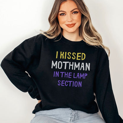 Person wearing a black nonbinary mothman sweatshirt with colorful text against a plain background