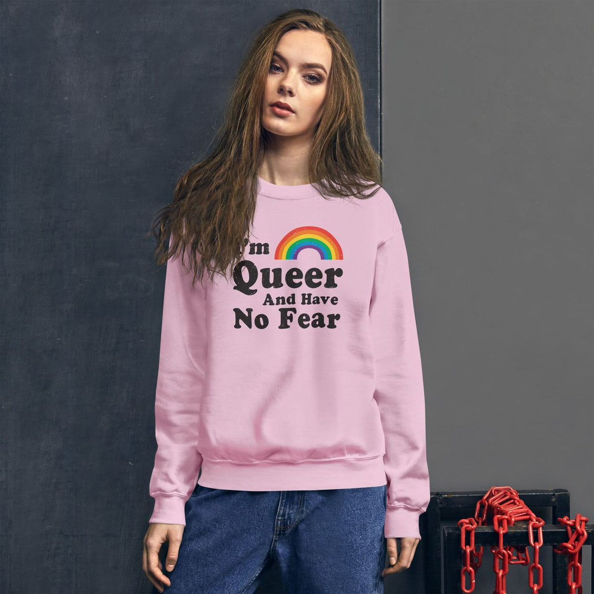 Queer Person wearing a pink pride lgbtq sweatshirt with a rainbow and text on a dark background