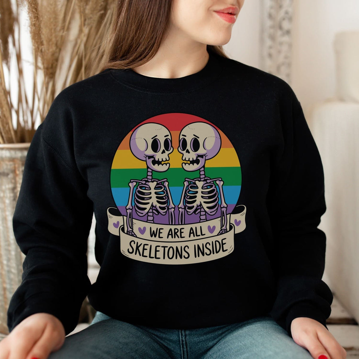 Person wearing a black sweatshirt with skeleton design and rainbow flag