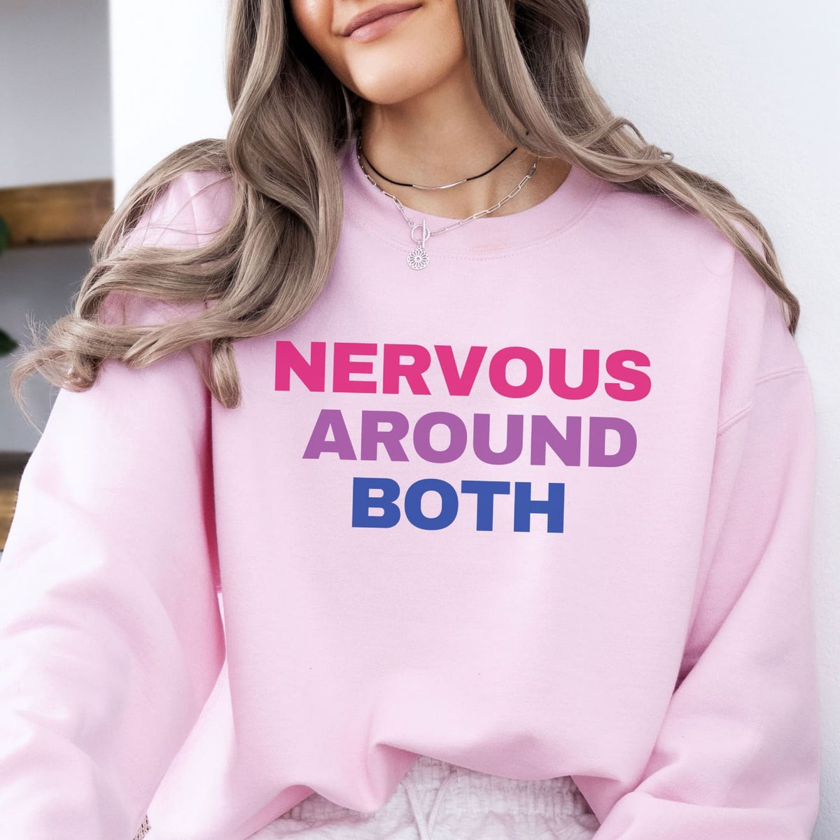 Person wearing a pink bisexual sweatshirt with 'NERVOUS AROUND BOTH' text.