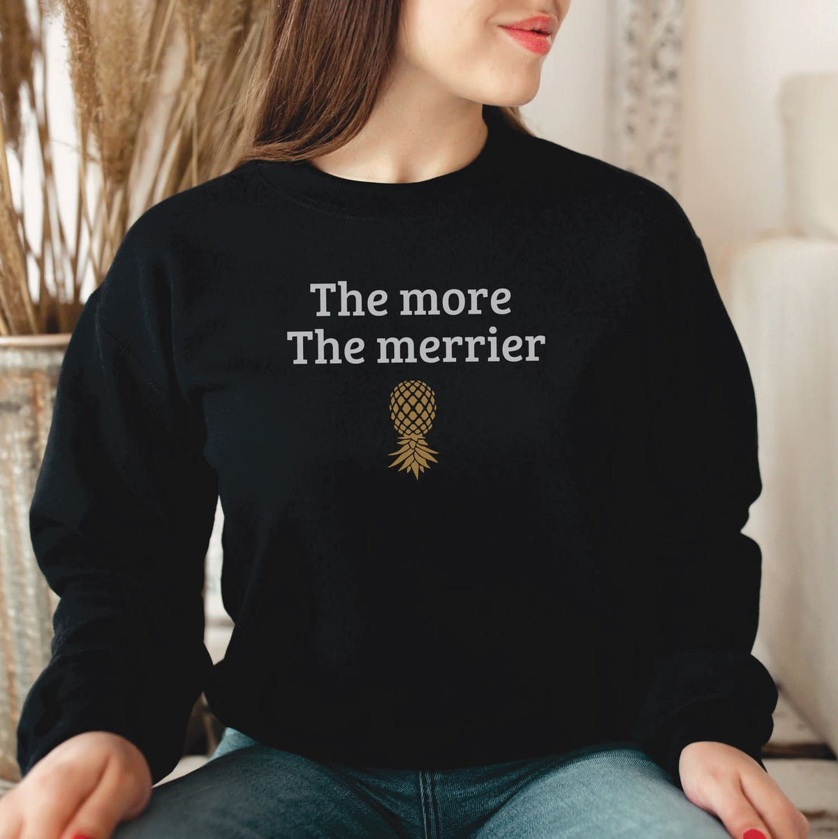 Person wearing a black swingers sweatshirt with 'The more The merrier' text and pineapple graphic.