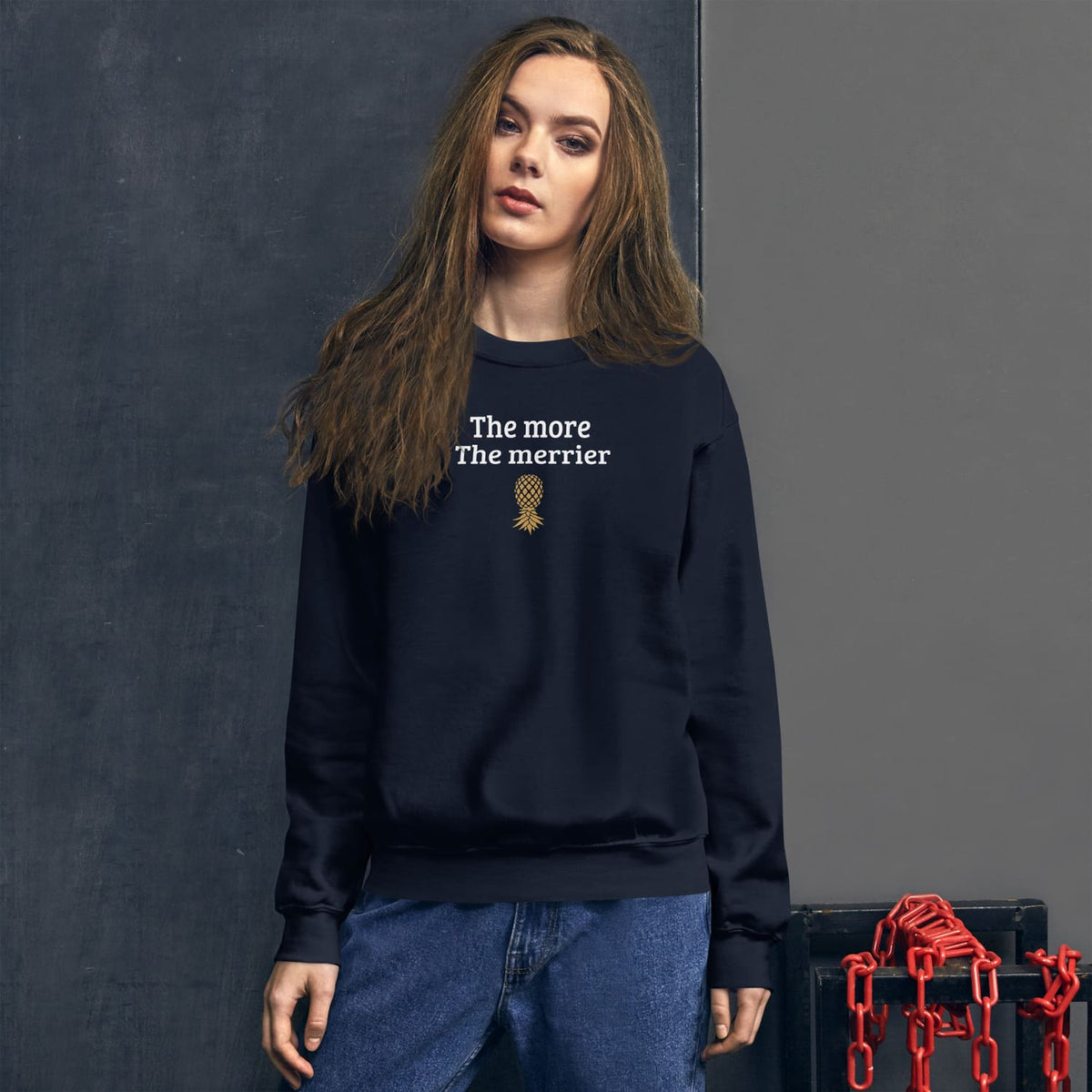 Person wearing a navy swingers sweatshirt with text and a pineapple graphic against a dark background
