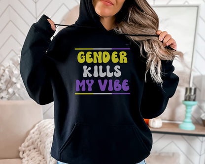 Person wearing a black nonbinary hoodie with colorful text 'GENDER KILLS MY VIBE' in a home setting.