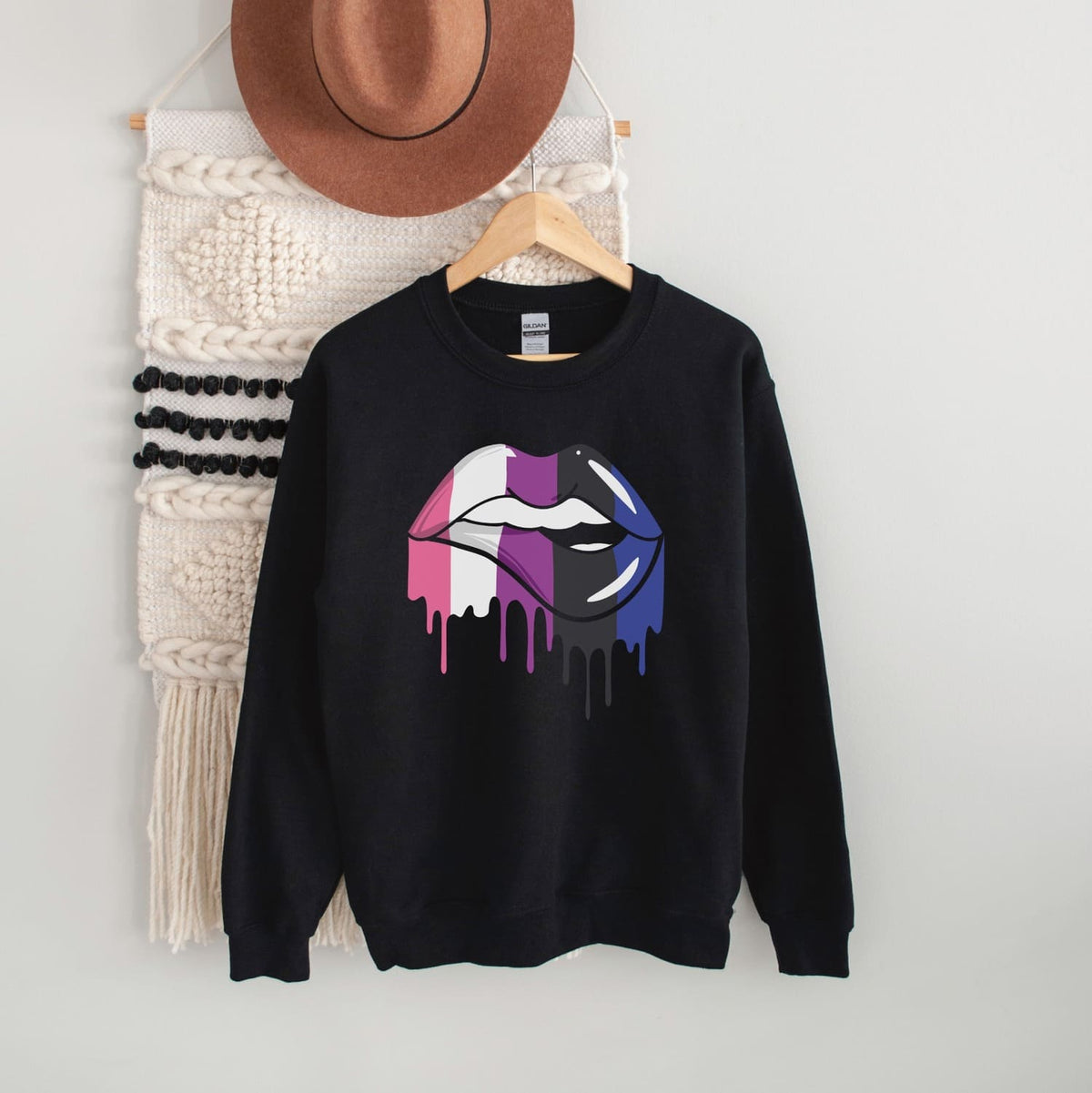 Gender fluid sweatshirt with a colorful lips design on a hanger against a white wall.