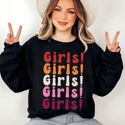 Person wearing a black sweatshirt with 'Girls! Girls! Girls!' text in lesbian sunset flag colors, making peace signs.