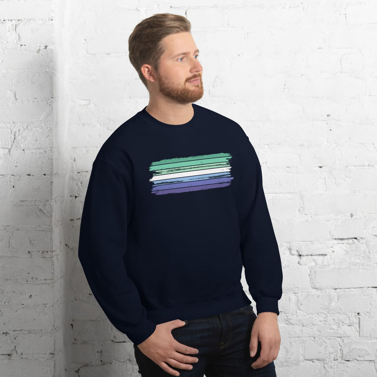 Man wearing a navy blue MLM sweatshirt with grunge flag graphic against a white brick wall.