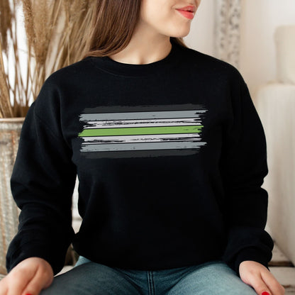 Person wearing a black agender sweatshirt with a graphic design sitting indoors.