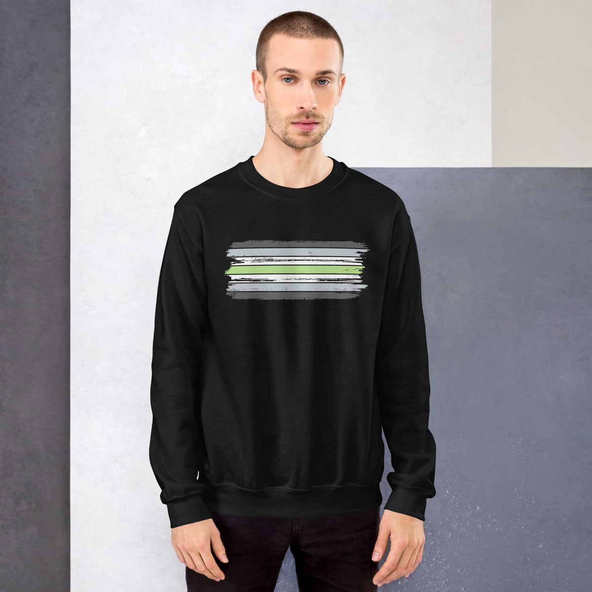 Man wearing a black agender sweatshirt with a graphic design on a plain background