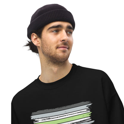 Man wearing a black beanie and black agender sweatshirt with a grunge flag  on a white background
