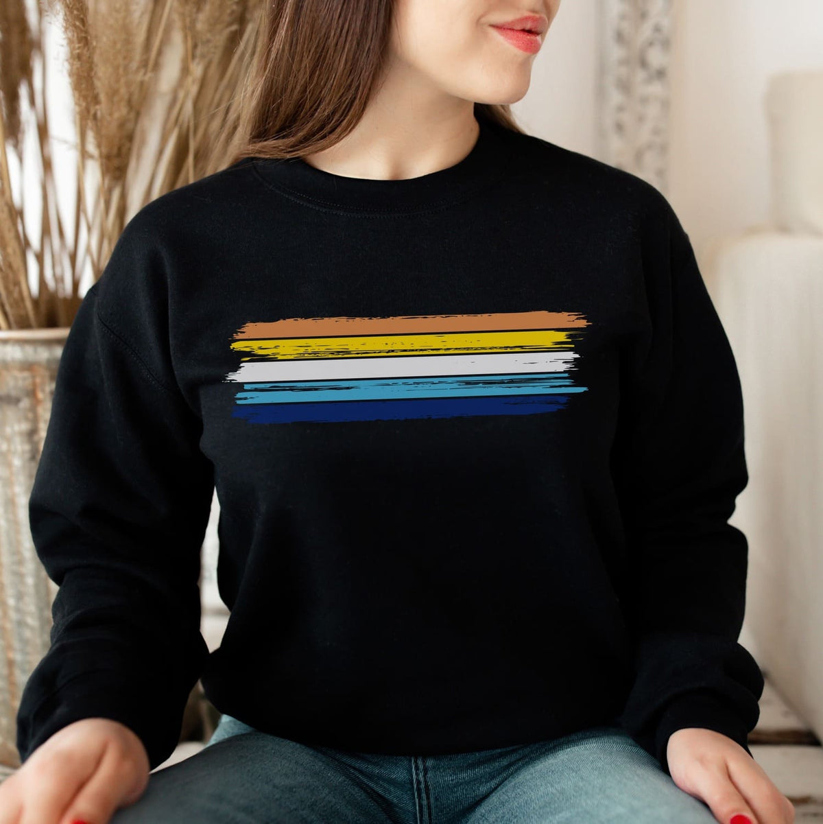 Person wearing a black aroace sweatshirt with grunge pride flag sitting indoors.