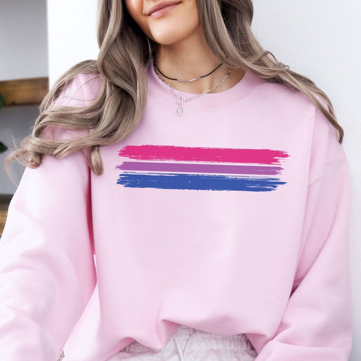 Person wearing a pink bisexual sweatshirt with grunge bi flag