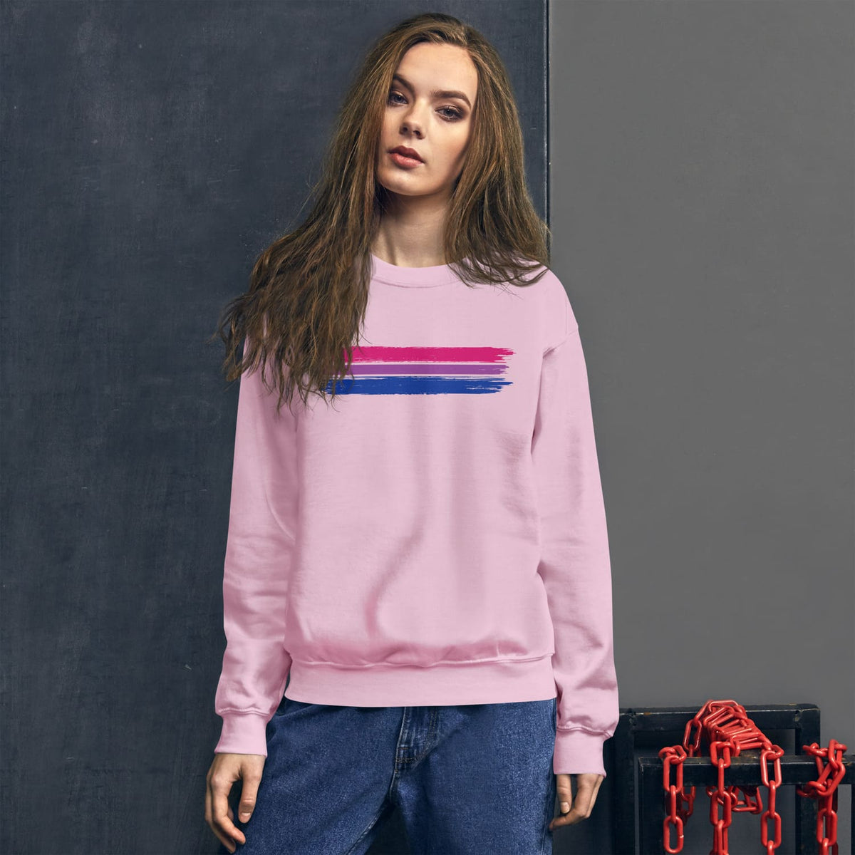 Woman wearing a pink bisexual sweatshirt with bi flag against a dark background