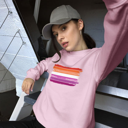 Person wearing a pink lesbian sweatshirt with colorful stripe design, sitting on a bench.