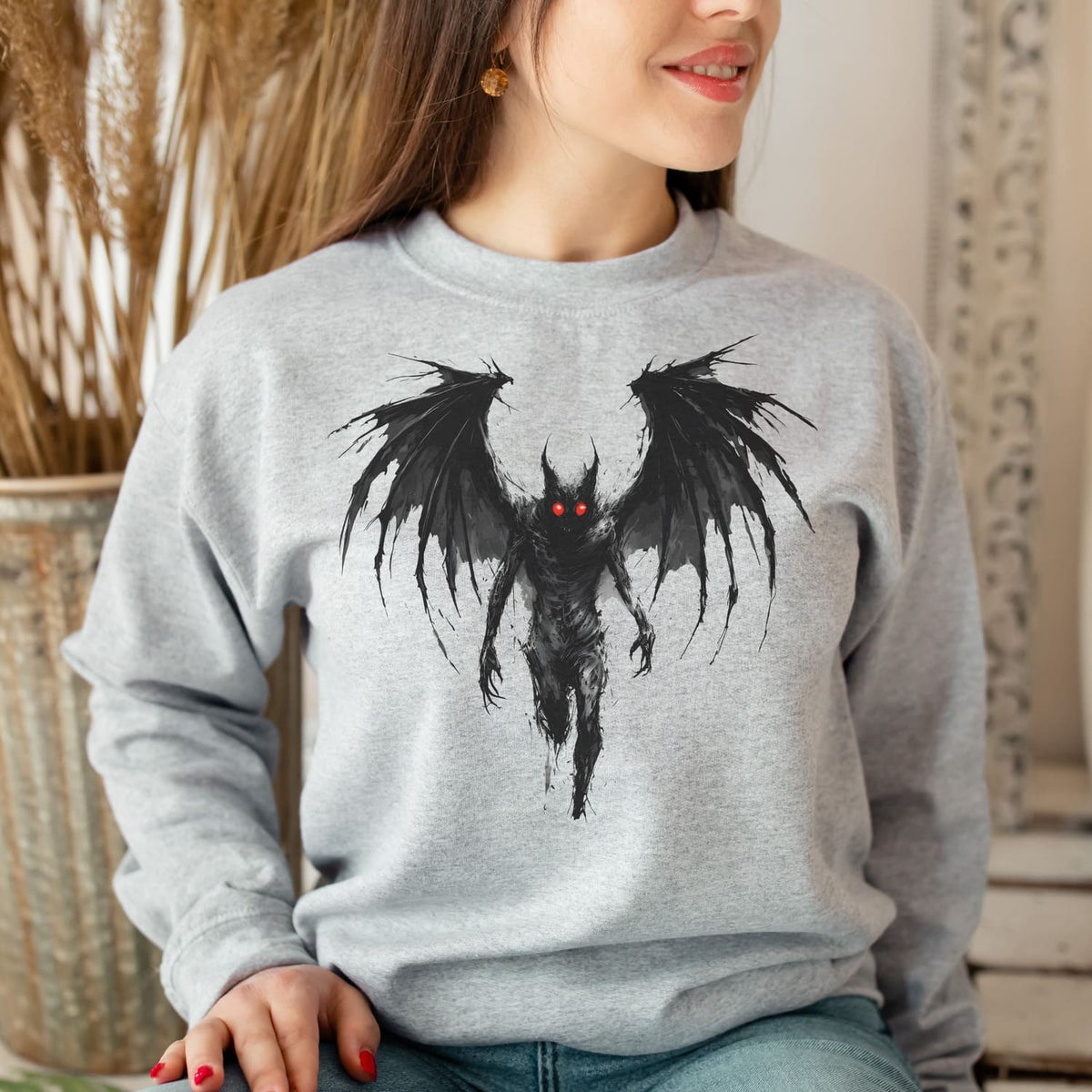 Person wearing a gray sweatshirt with mothman graphic