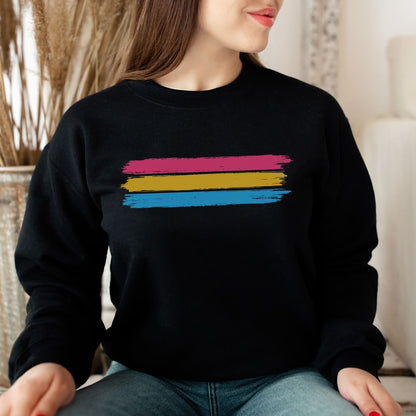 Person wearing a black pansexual sweatshirt with grunge flag stripes sitting indoors.