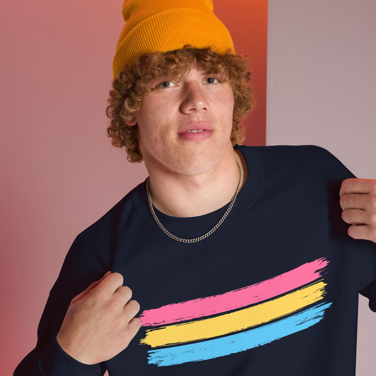 Person wearing a navy pansexual sweatshirt with pan pride colors on a gradient background