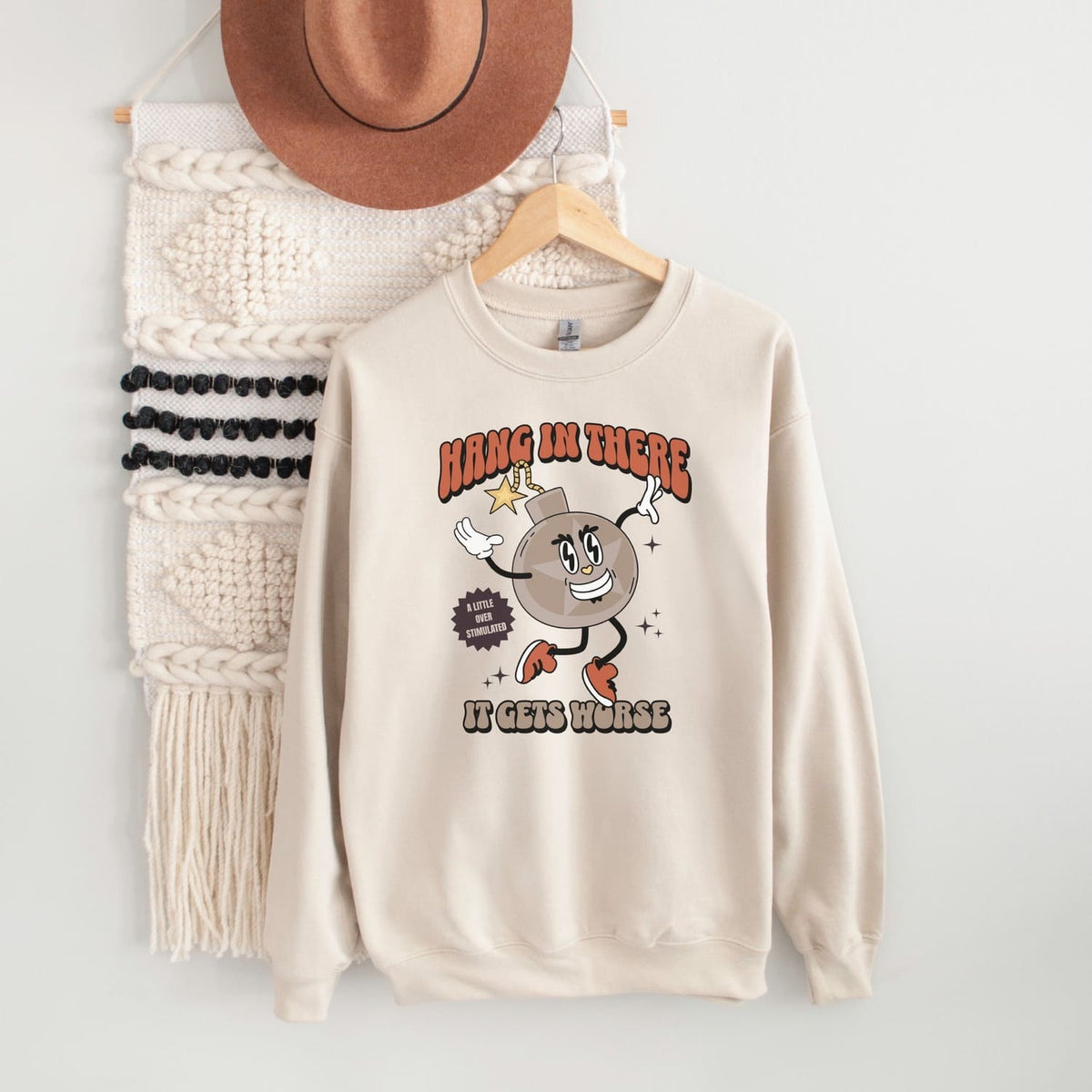 Beige mental health sweatshirt with cartoon character and text on a white background