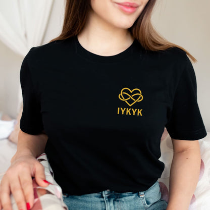 Person wearing a black t-shirt with a gold heart ENM design and 'IYKYK' text: Subtle Polyamory Shirt, Funny Open Relationship Tee, Polyamorous Pride T-Shirt, Non Monogamy, Polycule Gift For Big Middle Little Spoon