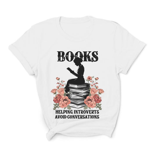 White t-shirt with a graphic of an introvert  person sitting on books, surrounded by flowers, and text on a white background.