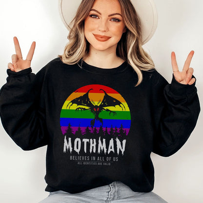 Person wearing a black lgbtq pride sweatshirt with a rainbow design and 'Mothman' text, making peace signs.