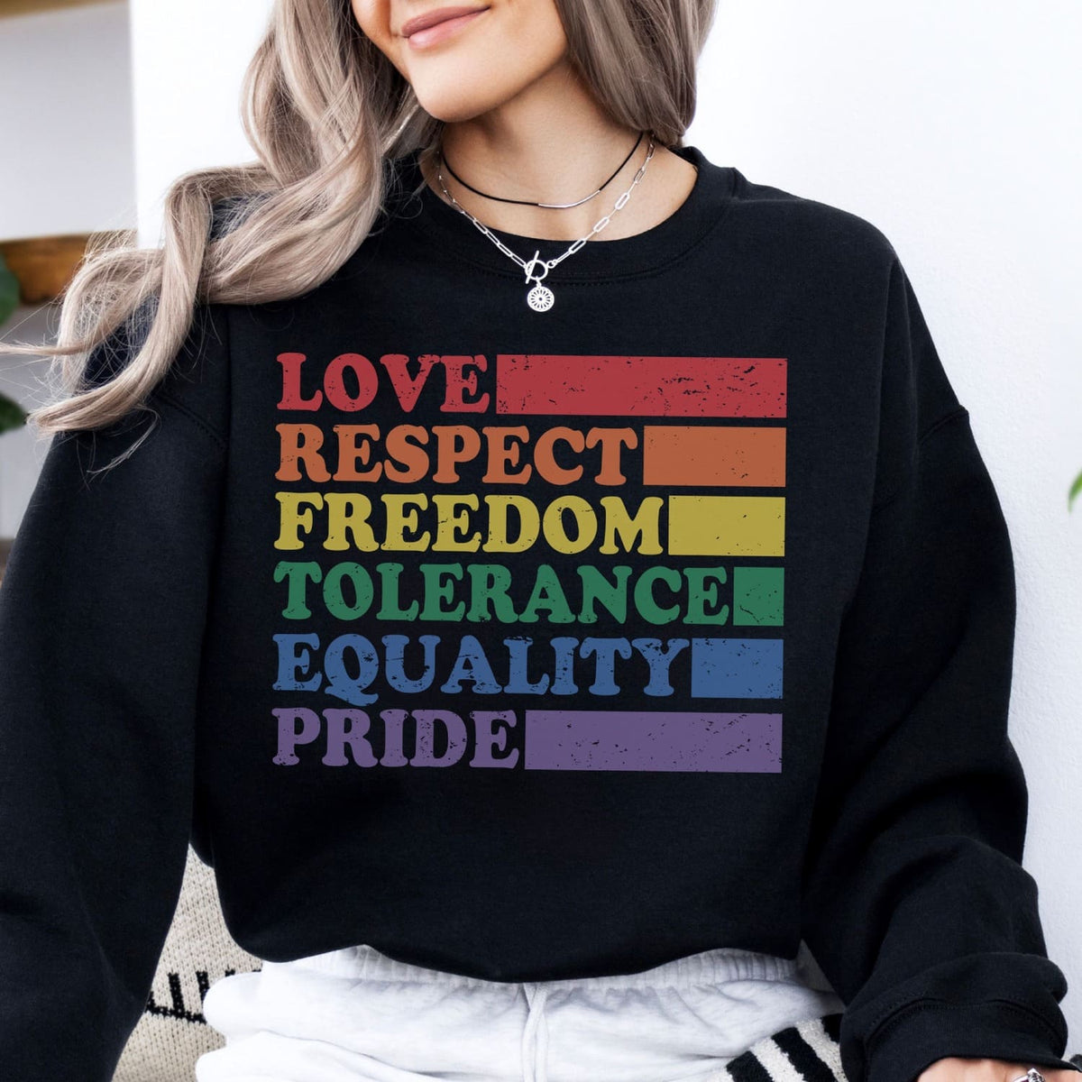 Person wearing a black LGBT pride sweatshirt with rainbow-colored text on a white background