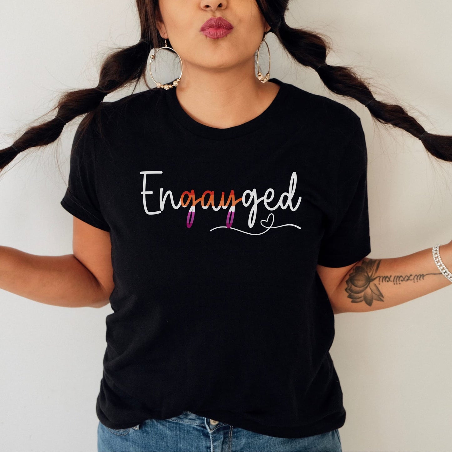 WLW woman wearing a black lesbian engagement t-shirt with 'Engayged' text, standing against a plain background