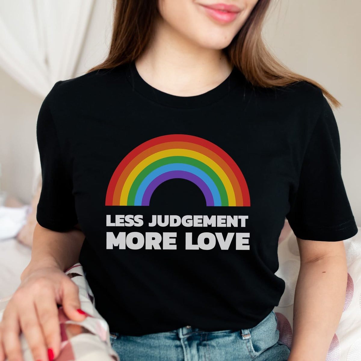 Person wearing a black pride t-shirt with a rainbow and text 'LESS JUDGEMENT MORE LOVE'.
