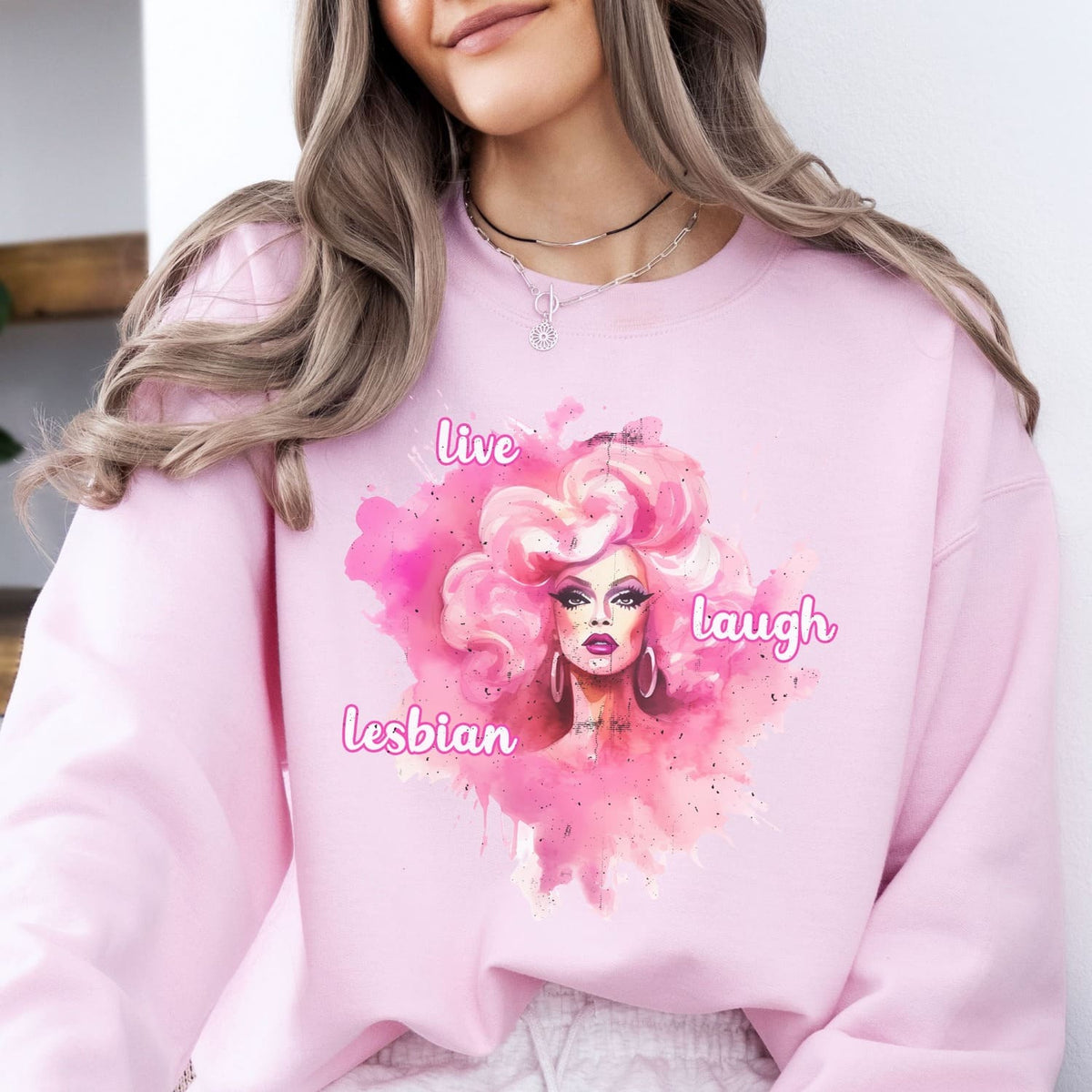 Person wearing a pink lesbian sweatshirt with a colorful graphic and text.