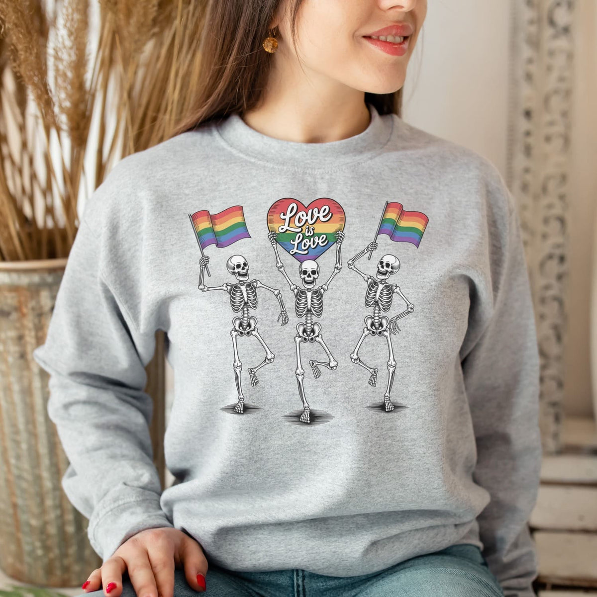 Person wearing a gray sweatshirt with skeletons holding rainbow flags and 'Love is Love' text.