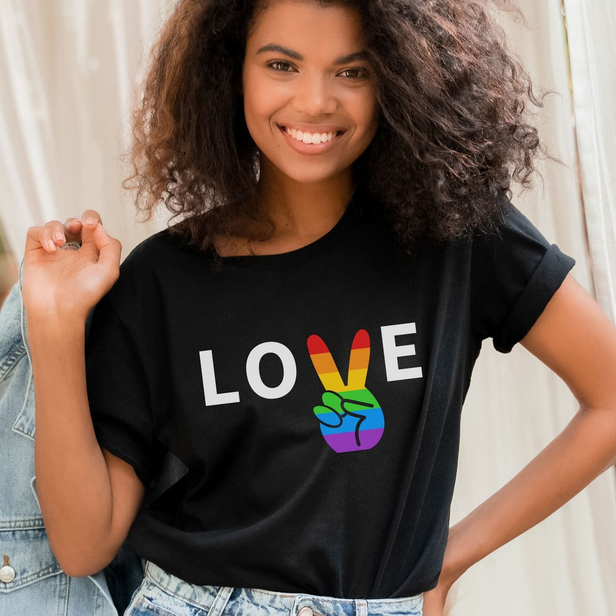 Person wearing a black t-shirt with 'LOVE' and rainbow peace sign design.
