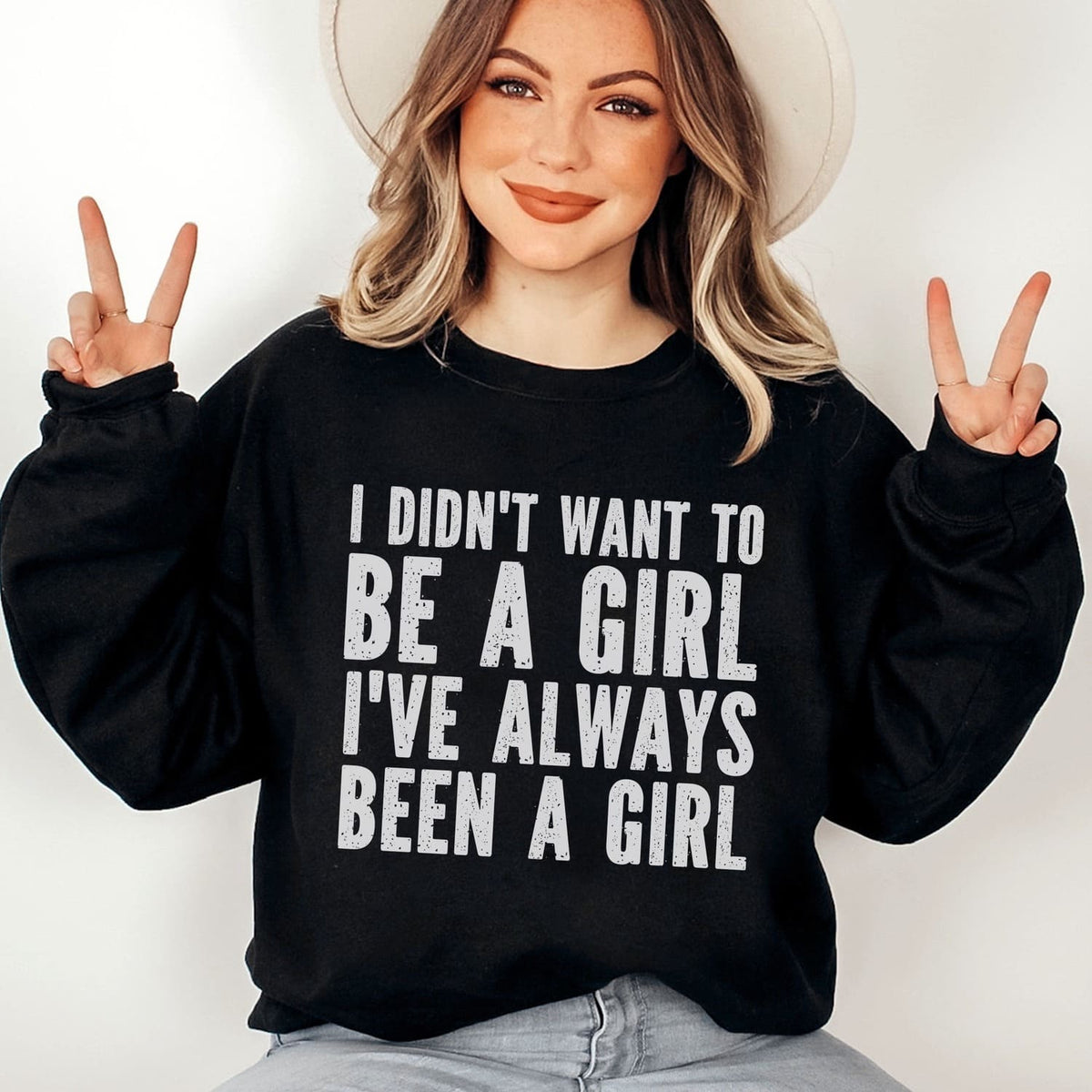 MTF trans person wearing a black sweatshirt with text, making peace signs.