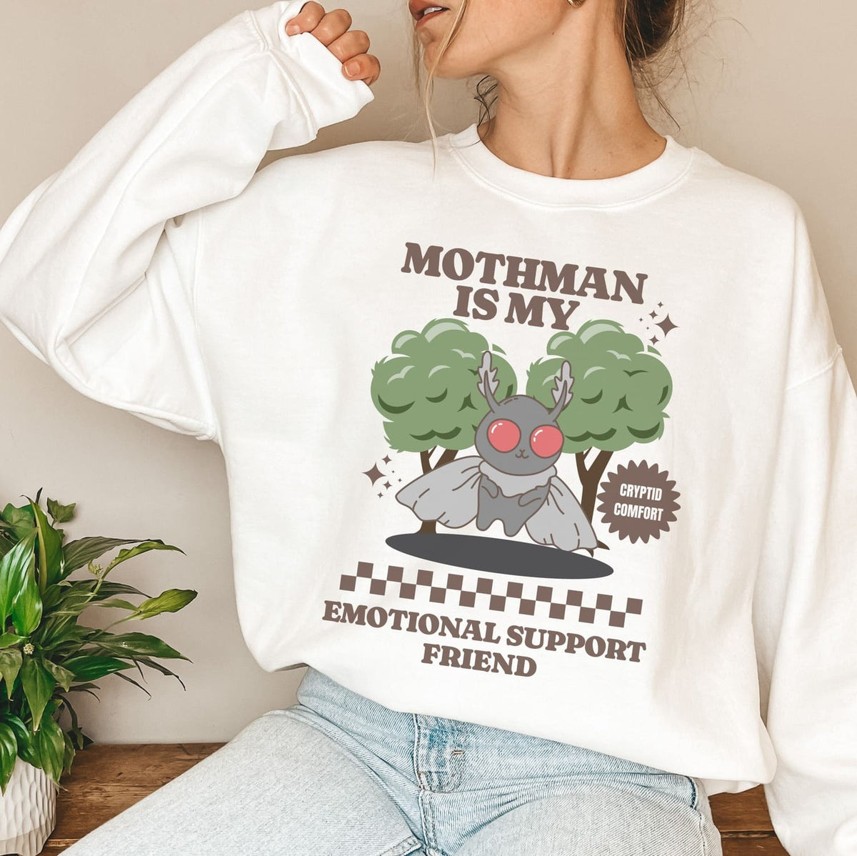 Person wearing a white mental health sweatshirt with a graphic design of Mothman and text.