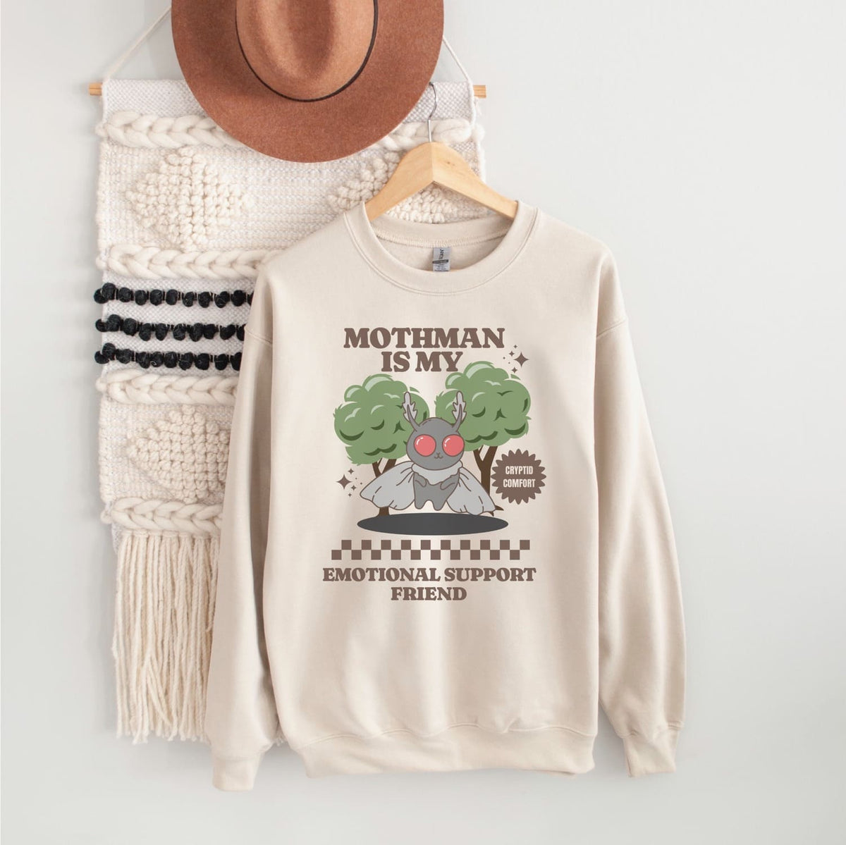 Beige mental health sweatshirt with Mothman graphic and text on a white background