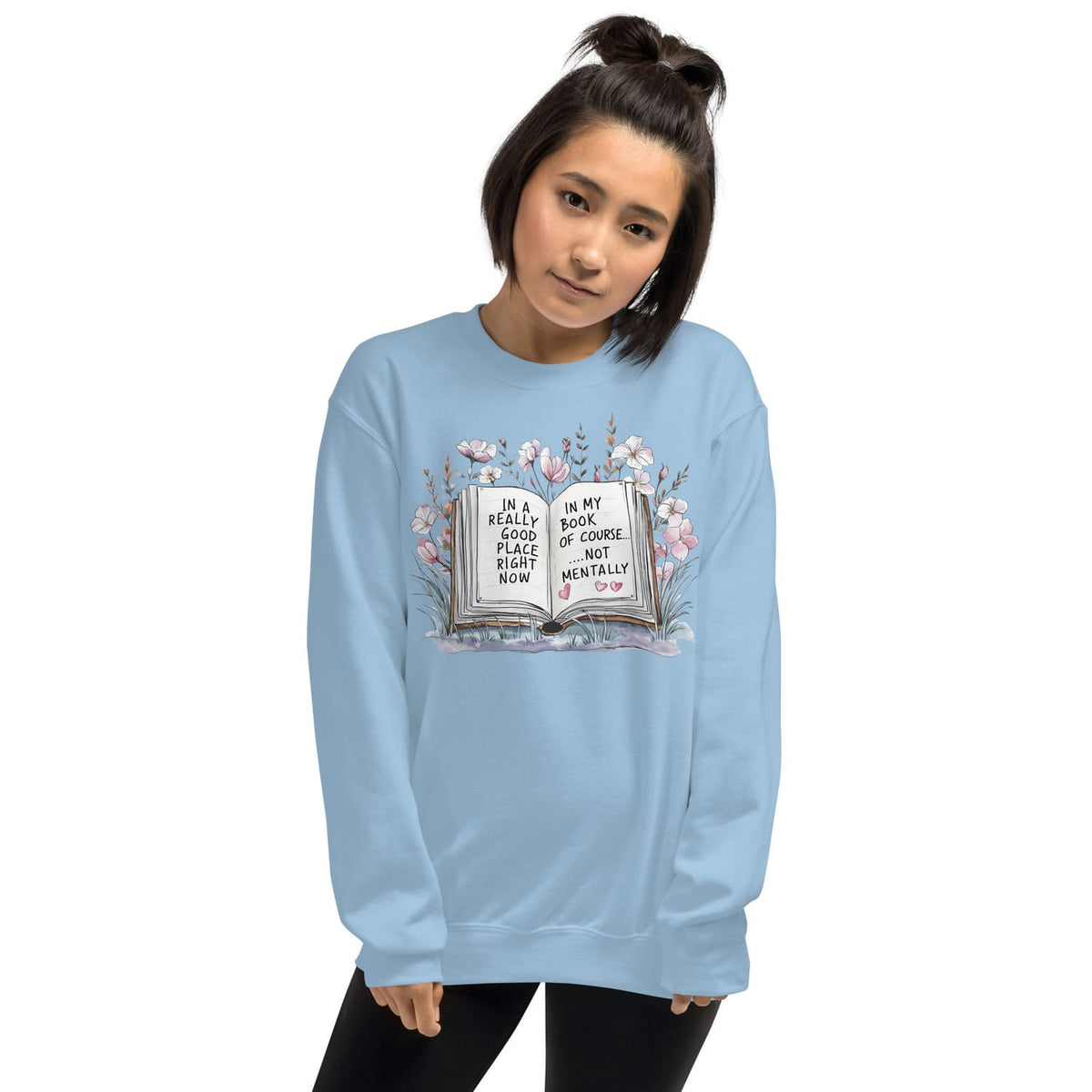 Person wearing a light blue mental health sweatshirt with a book and floral design on a white background