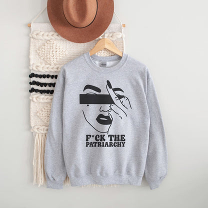 Gray sweatshirt with a feminist graphic design and text, placed on a white surface with a hat and bag in the background.