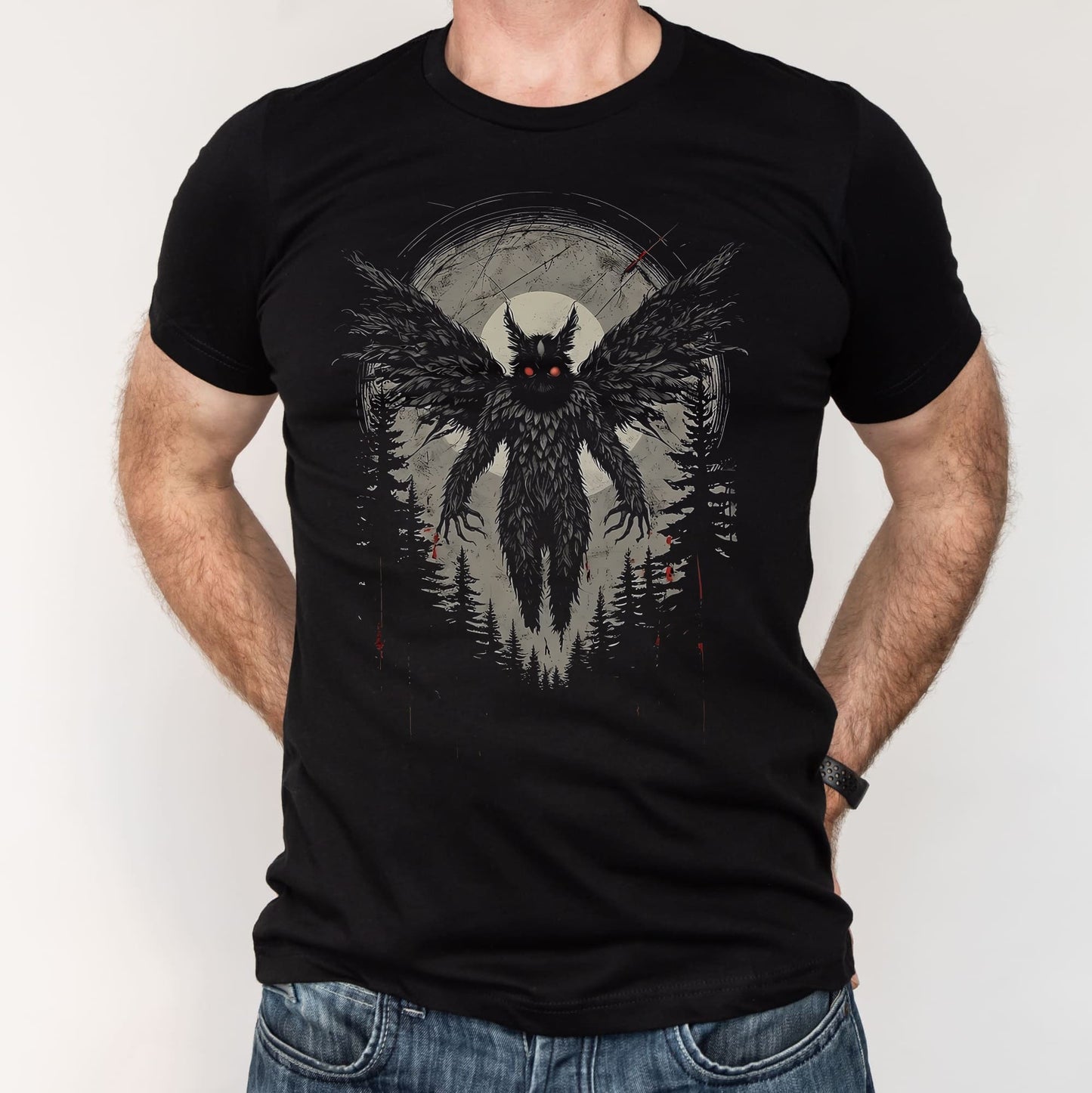 Black t-shirt with mothman graphic worn by a person on a plain background