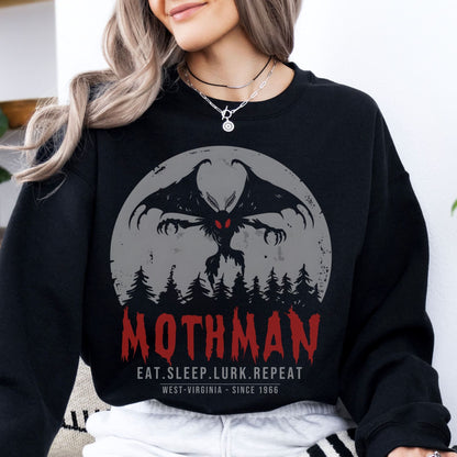 Person wearing a black sweatshirt with Mothman graphic and text