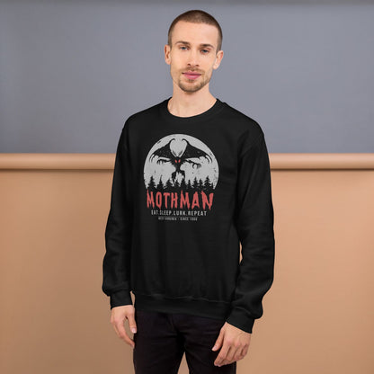 Person wearing a black sweatshirt with Mothman graphic and text