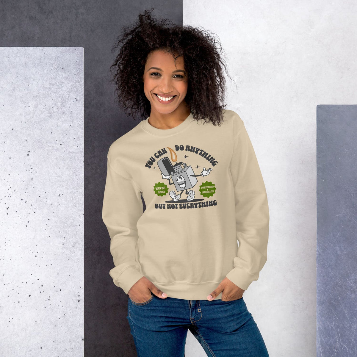 Woman wearing a beige burnout sweatshirt with motivational text, standing against a gray and white background.
