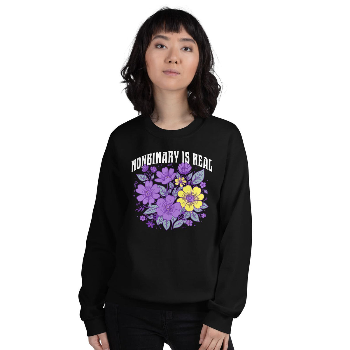 Person wearing a black sweatshirt with floral design and 'NONBINARY IS REAL' text on a white background
