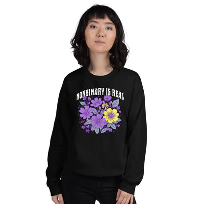 Person wearing a black sweatshirt with floral design and 'NONBINARY IS REAL' text on a white background