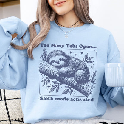 Person wearing a light blue sweatshirt with an overstimulated sloth graphic and text, holding a white mug.