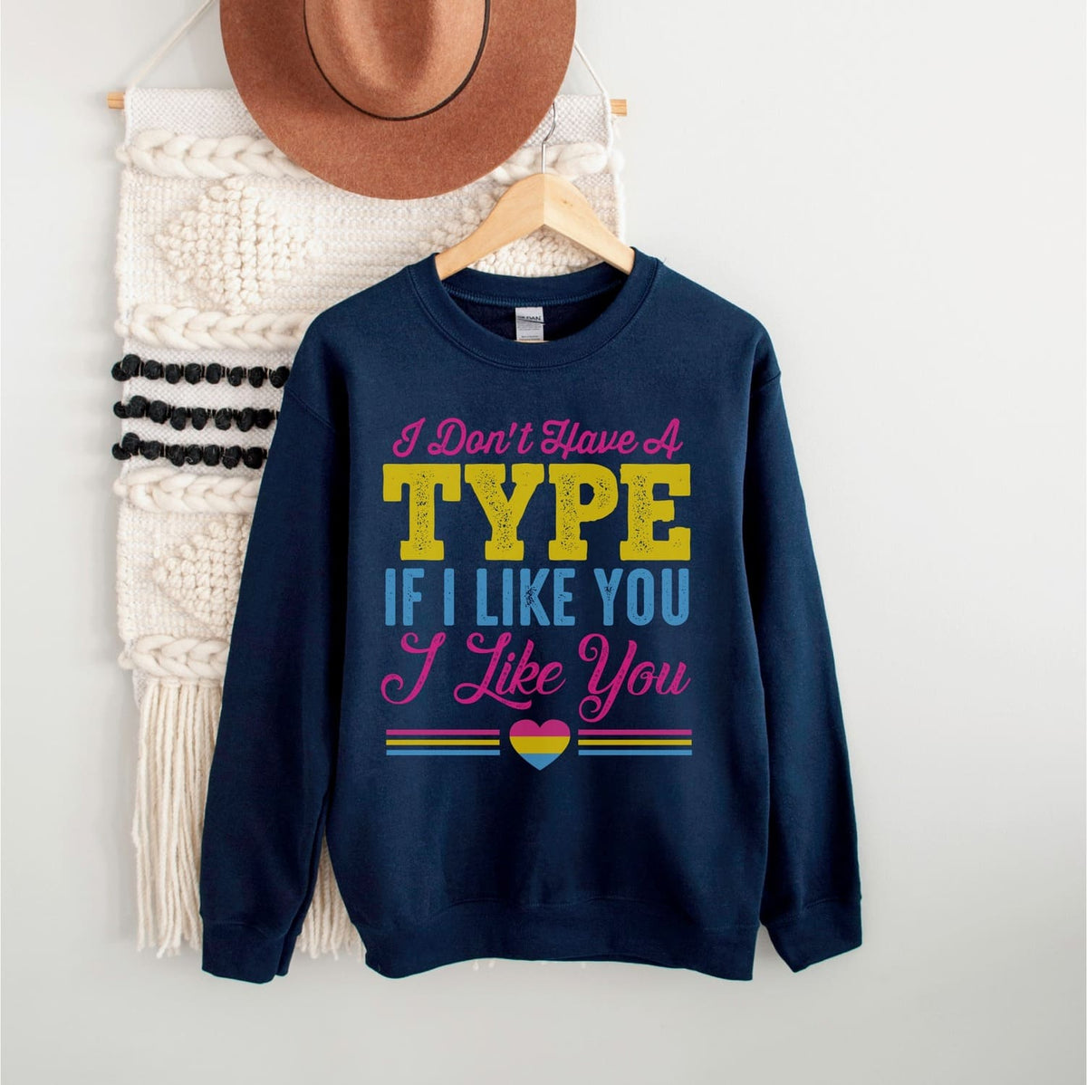 Navy blue pansexual sweatshirt with colorful text and pan heart graphic on a white background