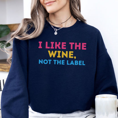 Person wearing a navy blue pansexual sweatshirt with colorful text 'I LIKE THE WINE, NOT THE LABEL'.